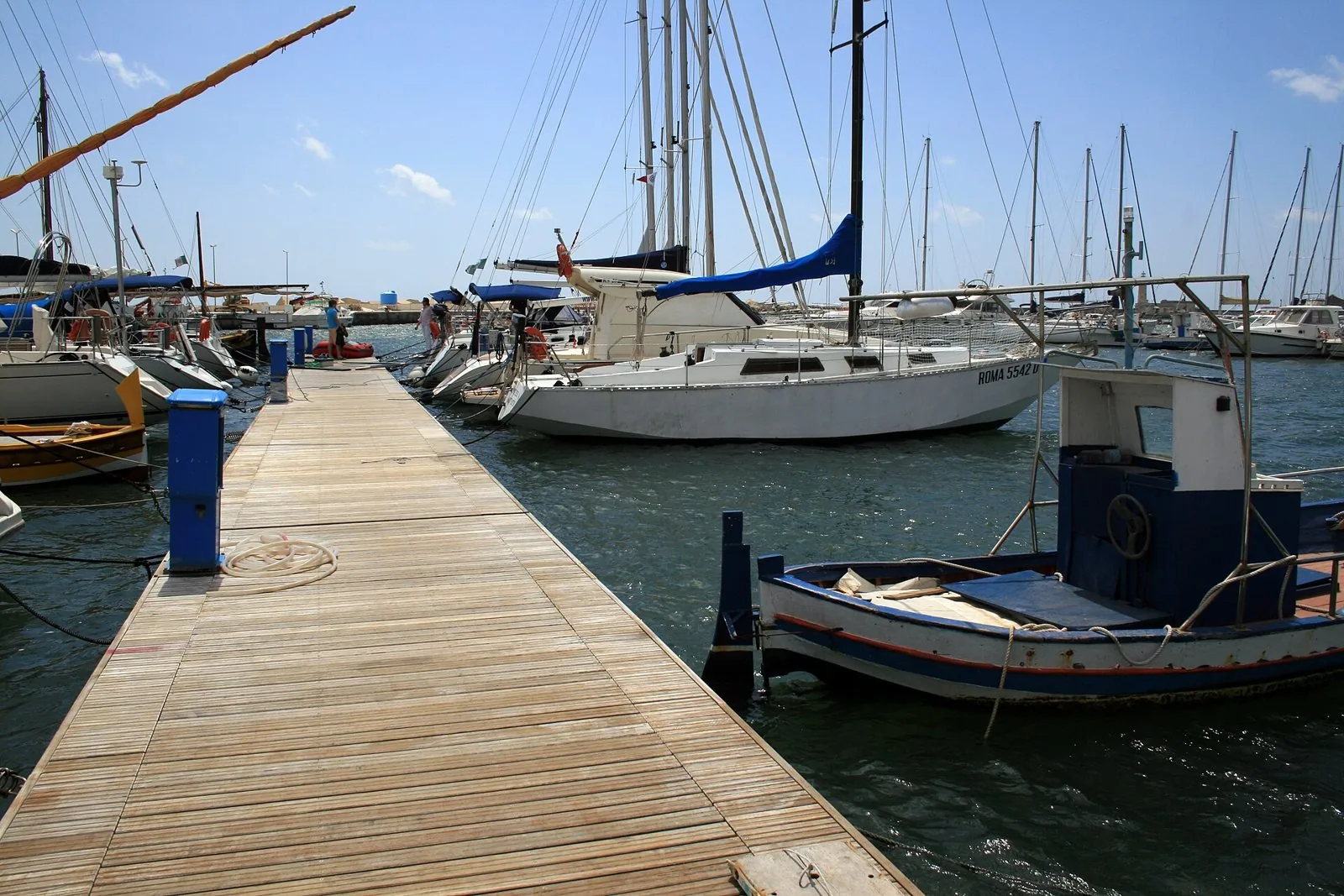 Pontile in legno del porto turistico di Marsala con barche a vela e una barca da pesca ormeggiate